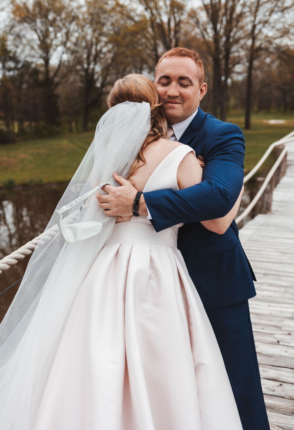 Wedding couple embracing on wooden dock during their first look photos.