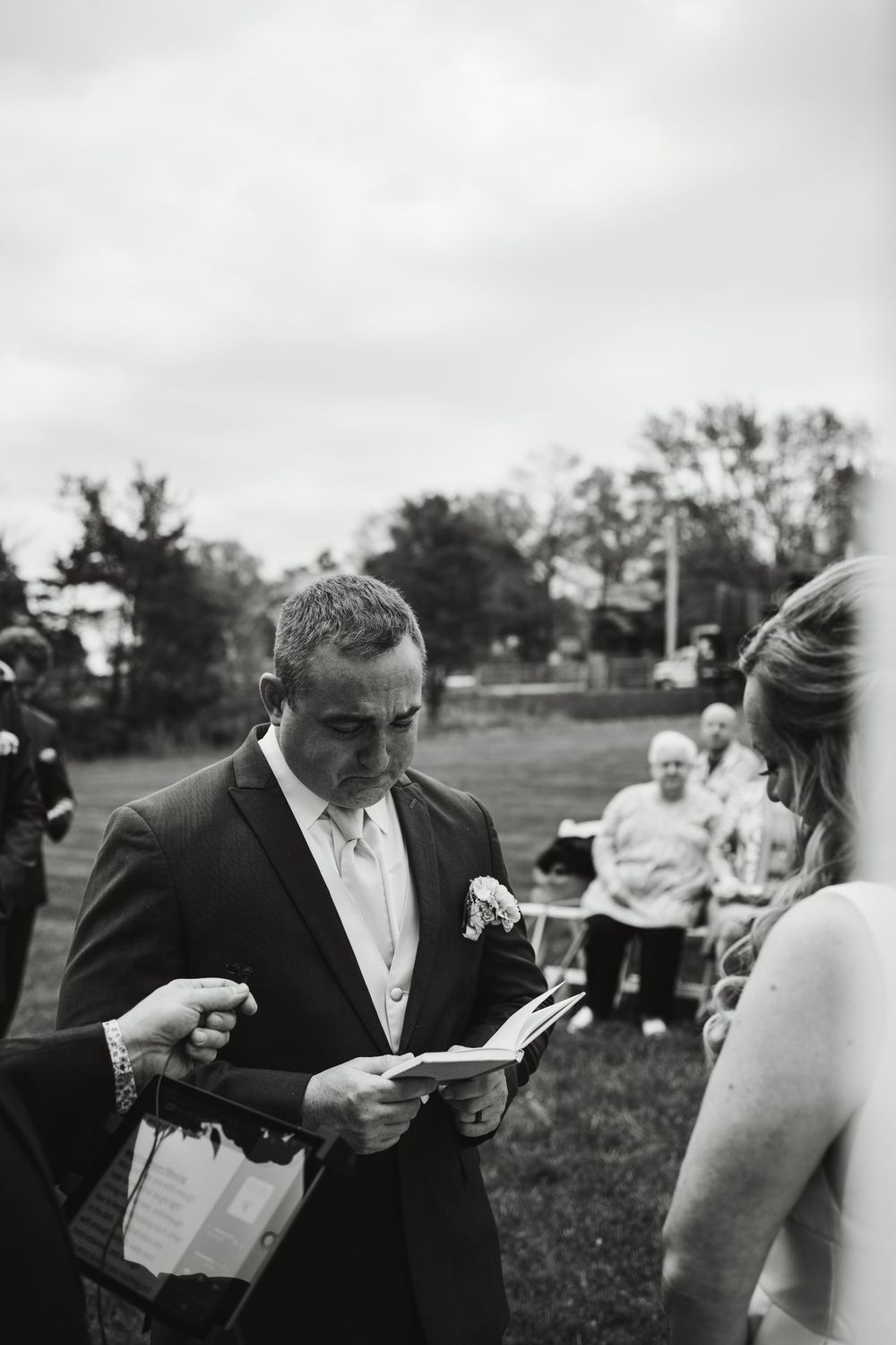 Black and white candid sequence of wedding couple reading letters to each other outdoors.