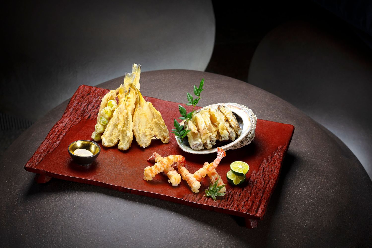 Dramatic food presentation with green teapot pouring liquid into white bowl garnished with flowers.
