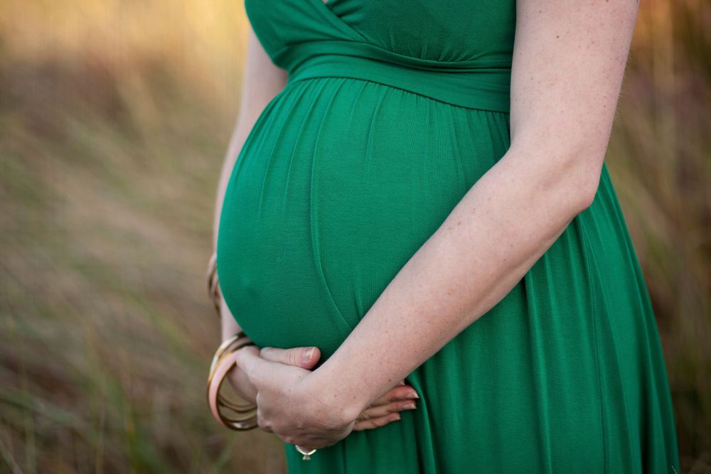 Close-up shots of emerald green maternity dress showing baby bump details.