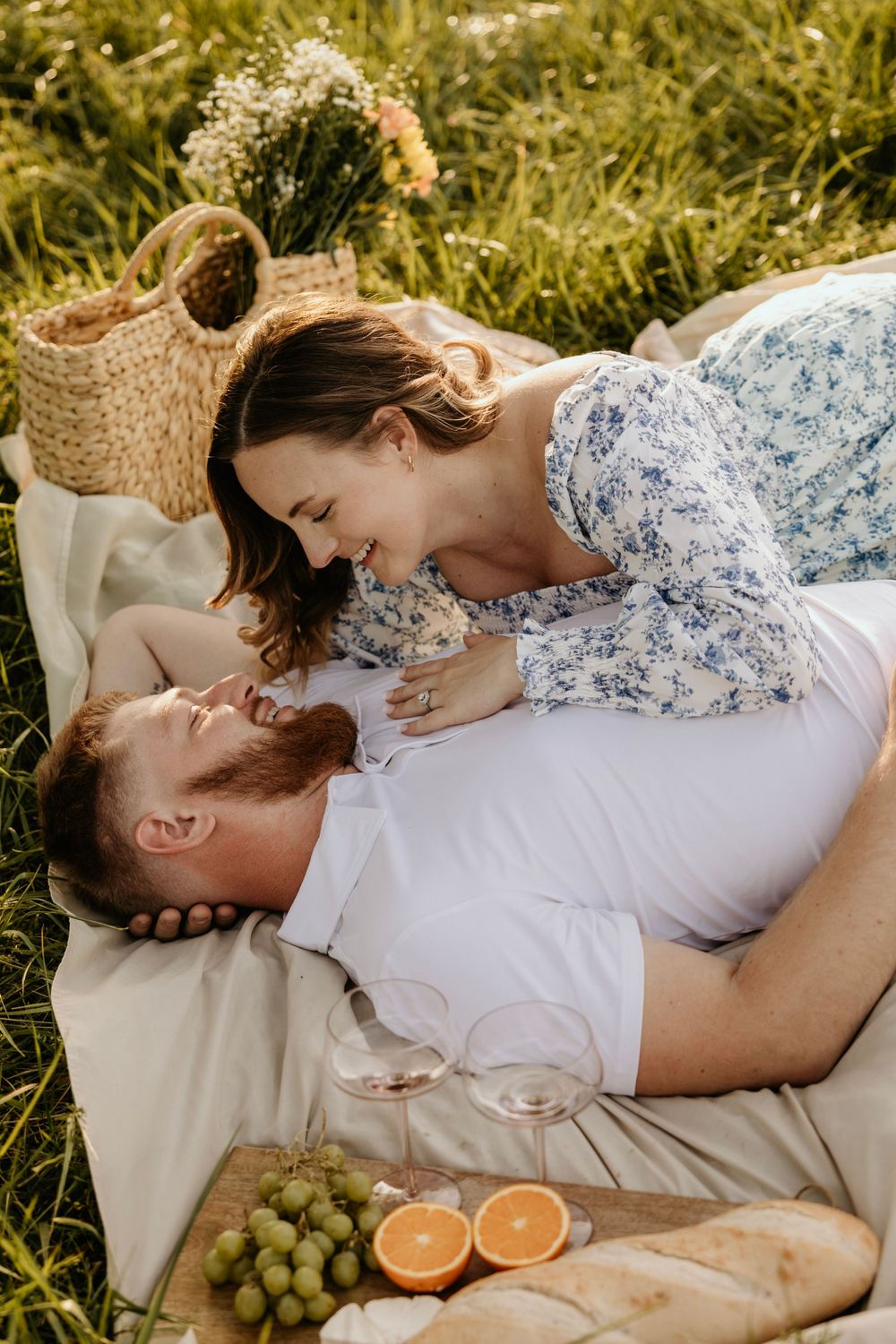 Romantic picnic setting with couple on blanket surrounded by fruit and woven basket.