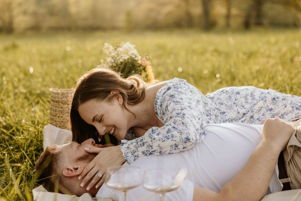 Intimate moment between couple during outdoor picnic with golden sunlight filtering through.