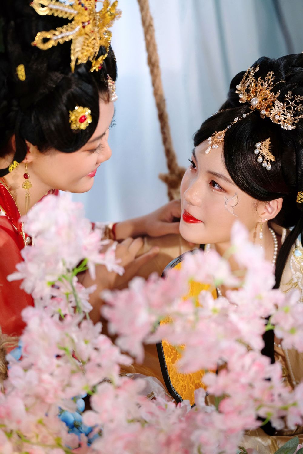 Elegant backlit studio portrait of mother and daughter in Tang Dynasty Hanfu on a swing among wisteria, by Imagine Image Studio.
