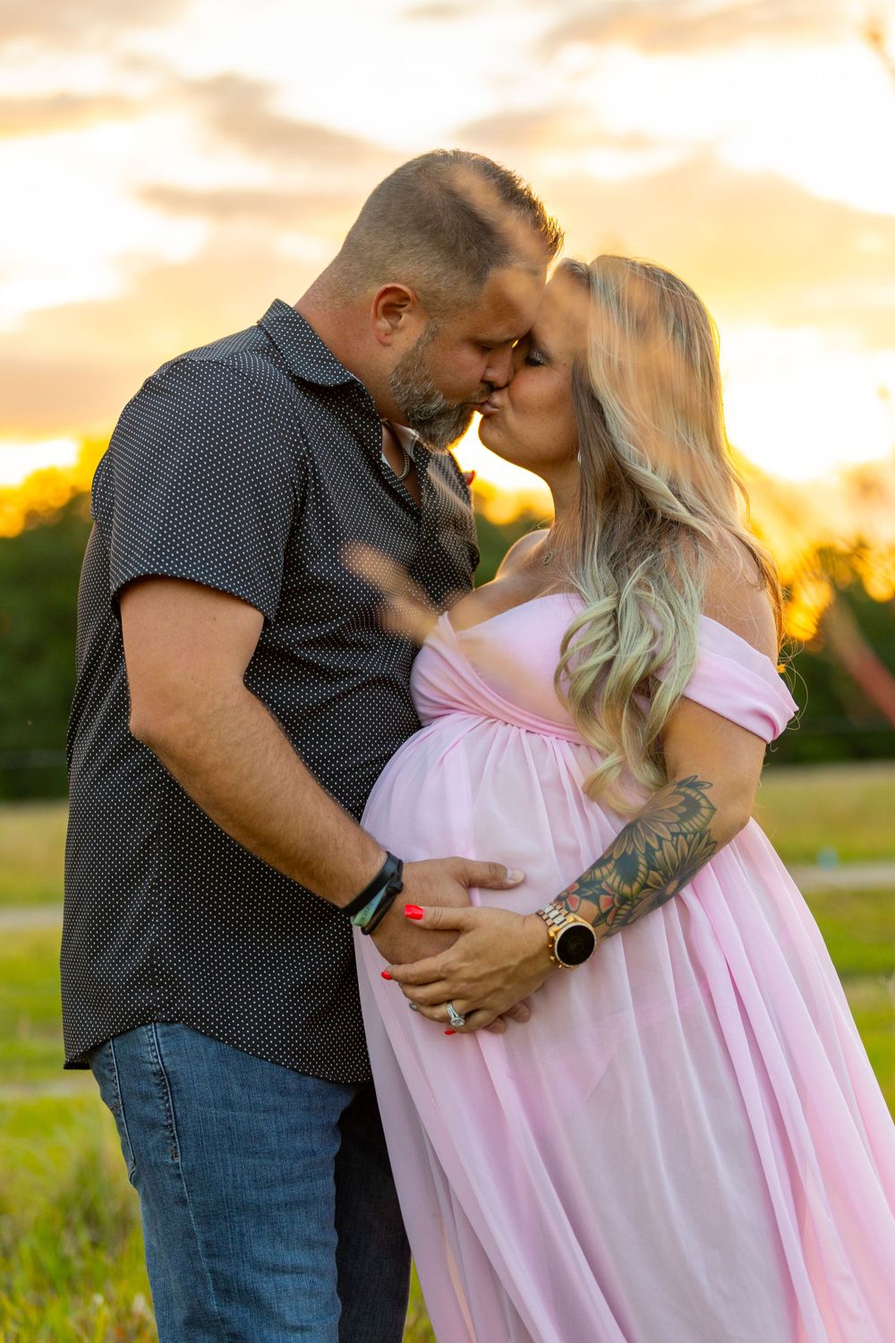 Romantic maternity photo of couple embracing at sunset in a golden field. Geneva, Florida