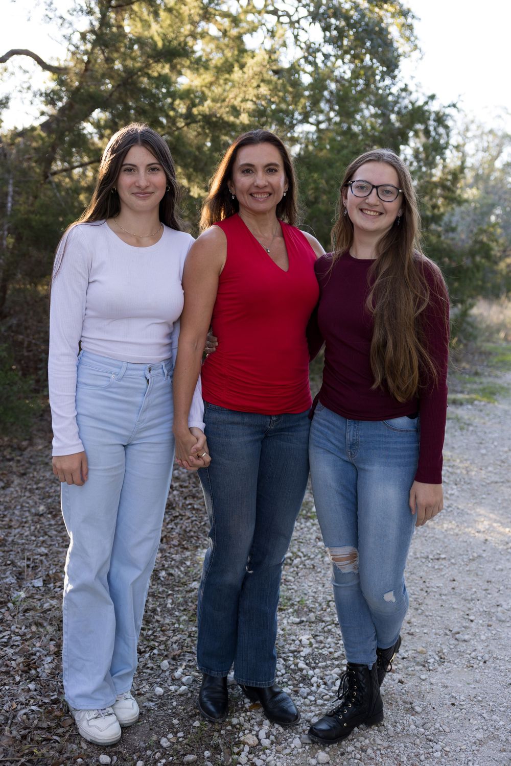 Three people in casual attire stand together on outdoor pathway.