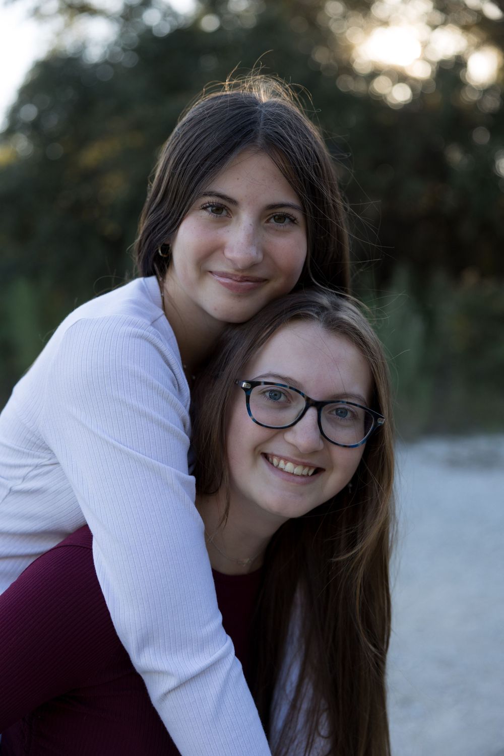 Two people share a joyful embrace while posing for a casual outdoor portrait.