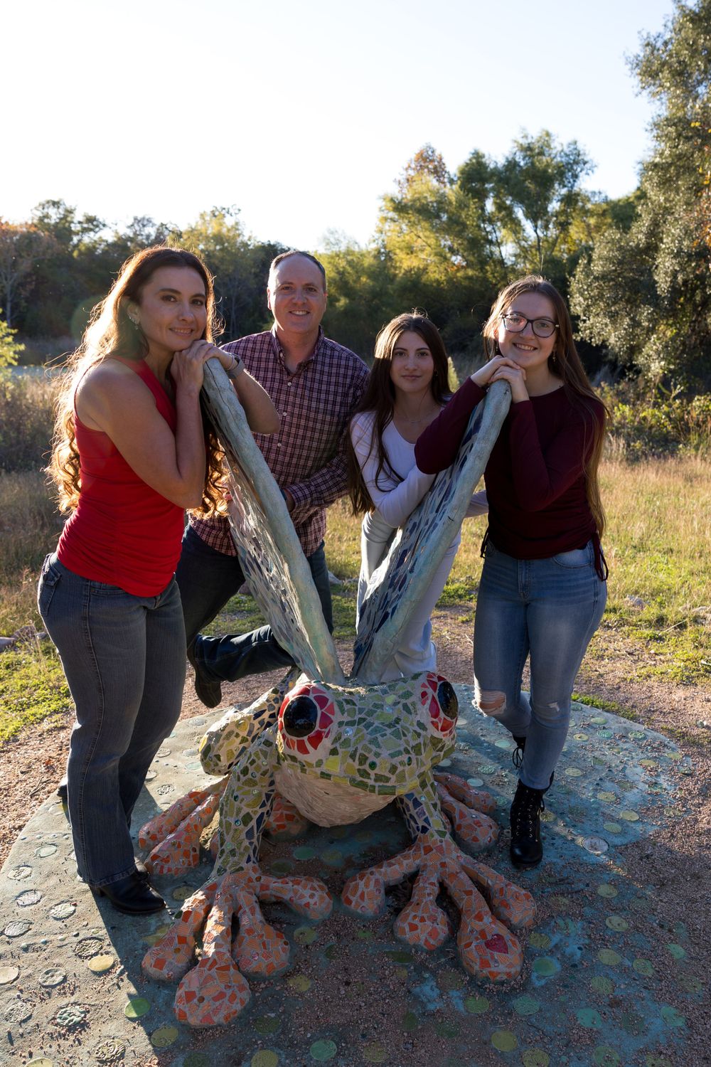 Group posing with a decorative turtle sculpture on an outdoor trail.