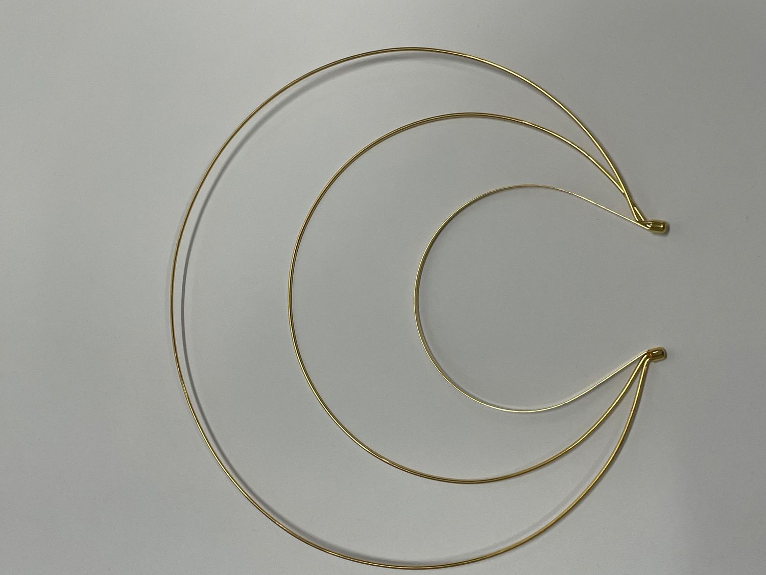 Minimalist gold wire headpiece with spiral design wrapping around in a circular shape.