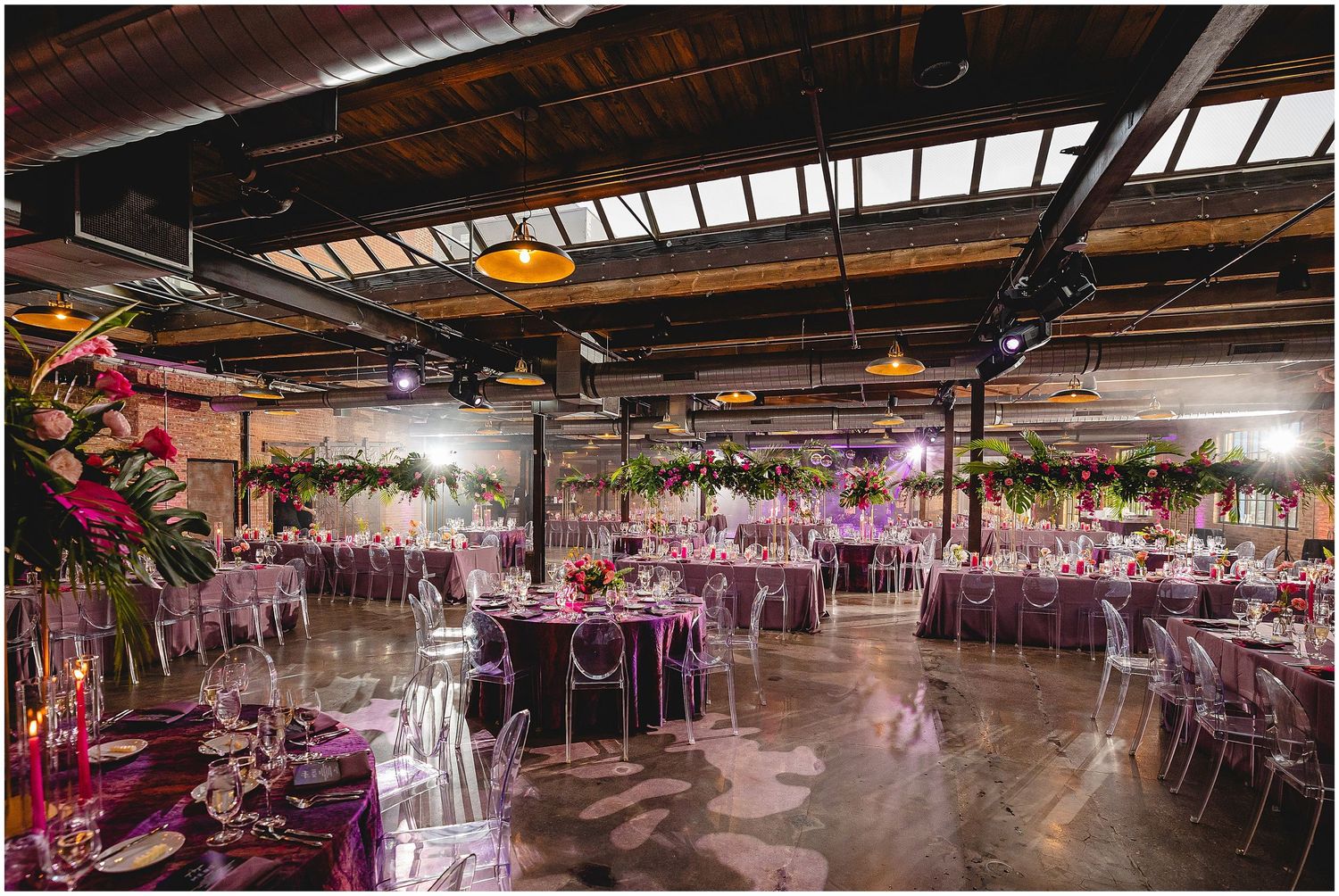 Industrial wedding reception venue with pink floral centerpieces and elegant table settings.