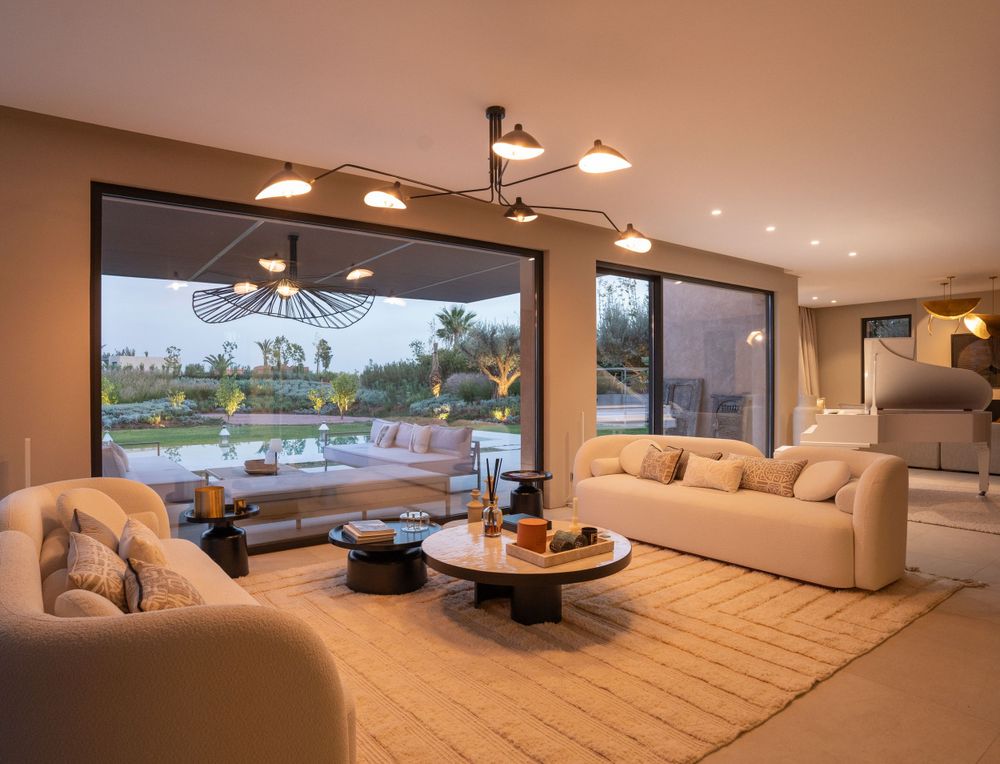 Elegant living room with modern lighting fixtures and panoramic views of outdoor pool.