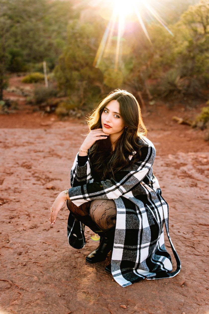 Cozy autumn portrait in plaid blanket with dramatic sunset lighting on Sedona red rocks.