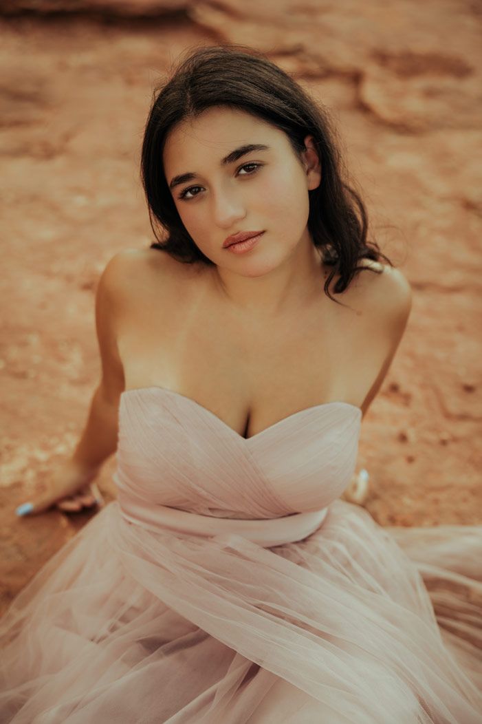 Portrait of woman in pink tulle dress on Sedona red rock terrain.