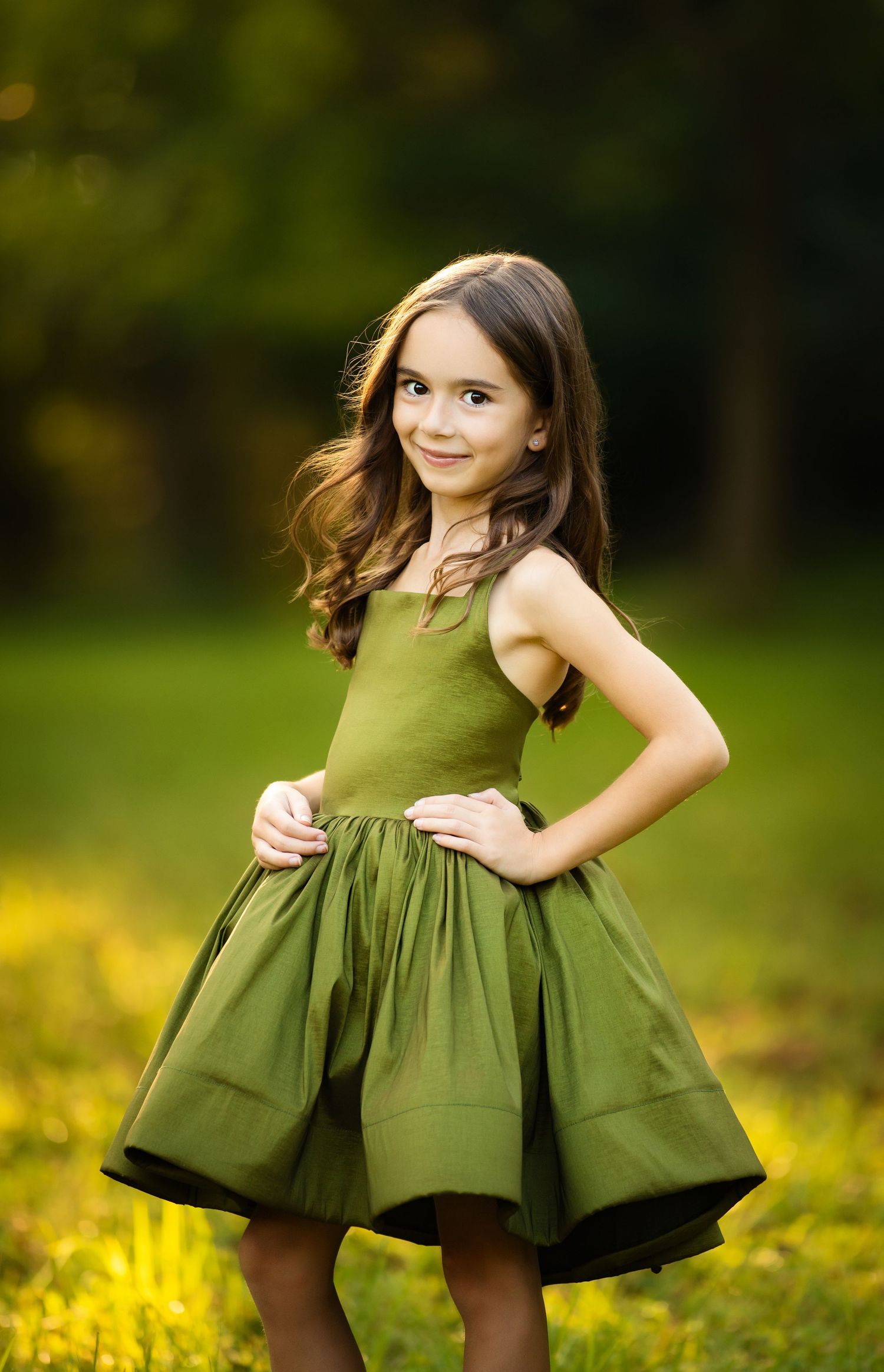 A flowing olive green dress twirls gracefully in an enchanted autumn forest setting with golden sunlight.