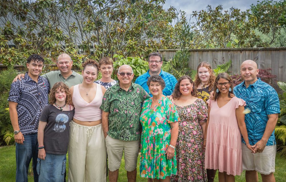 Large family group portrait outdoors wearing colourful casual clothes.