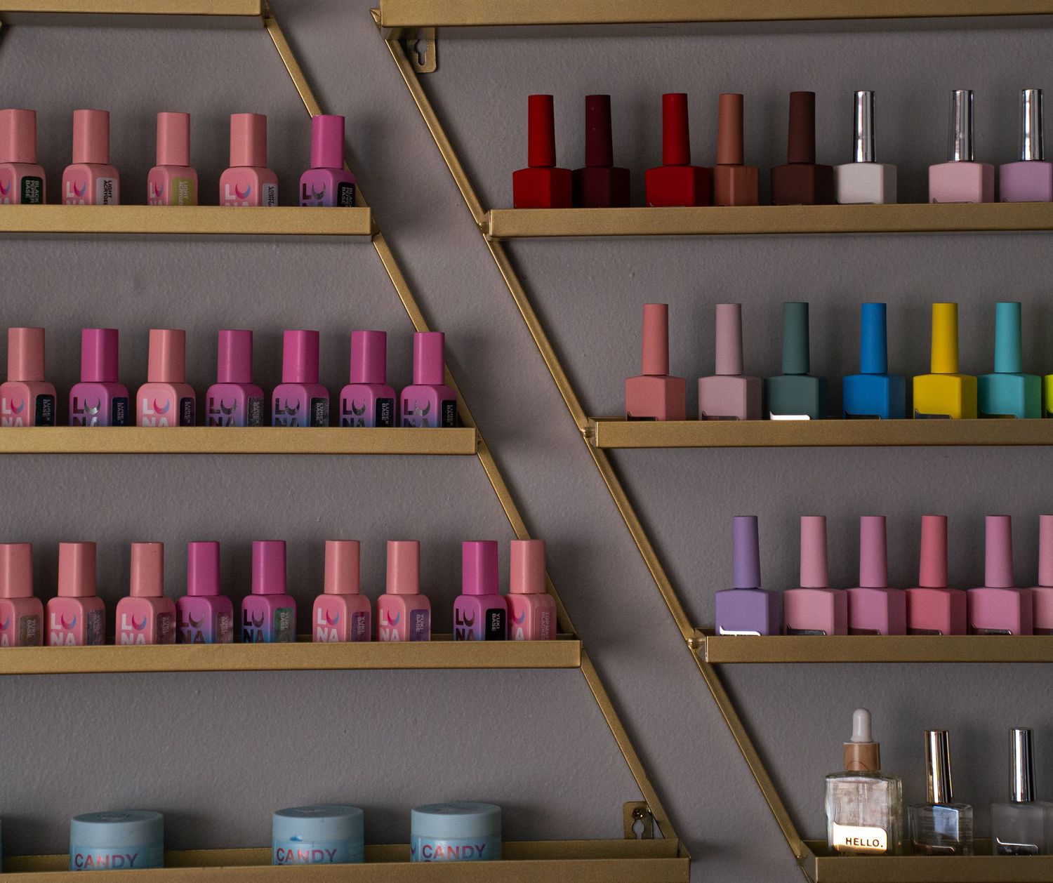 Colorful nail polish bottles arranged on wooden shelves in a beauty salon display.