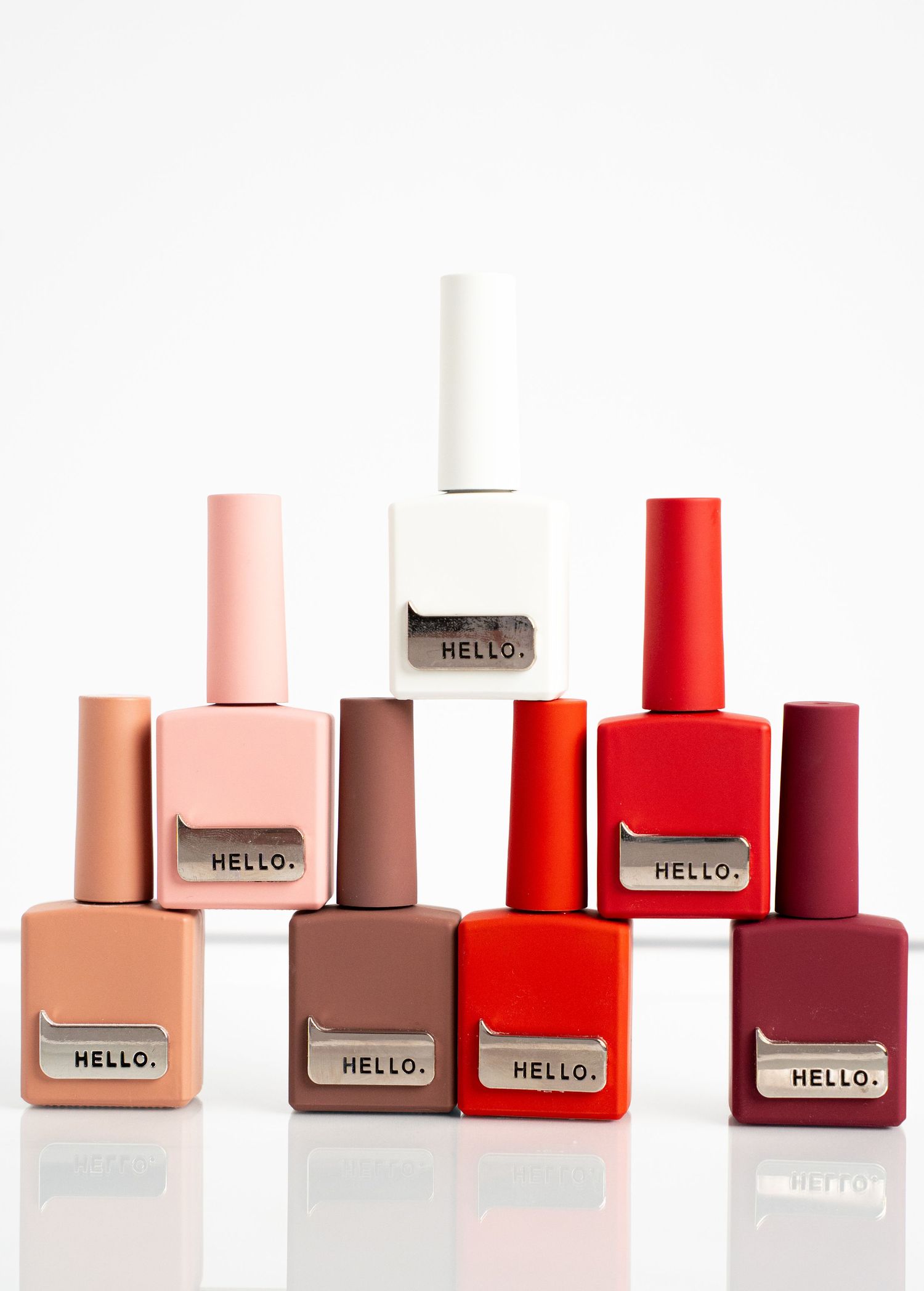 Collection of neutral and red nail polish bottles arranged in ascending order against white background.