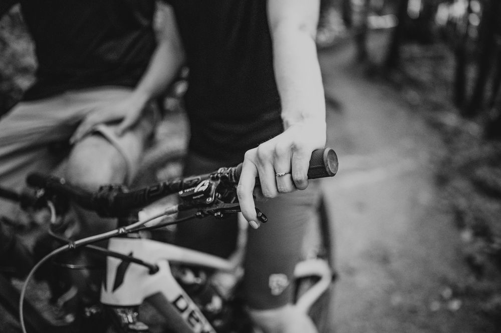 Couple adventure photography photoshoot on Vancouver Island of couples hand with engagement ring on bike handle