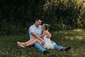 A romantic couple sits together on a blanket in a sunlit meadow during a summer afternoon picnic.