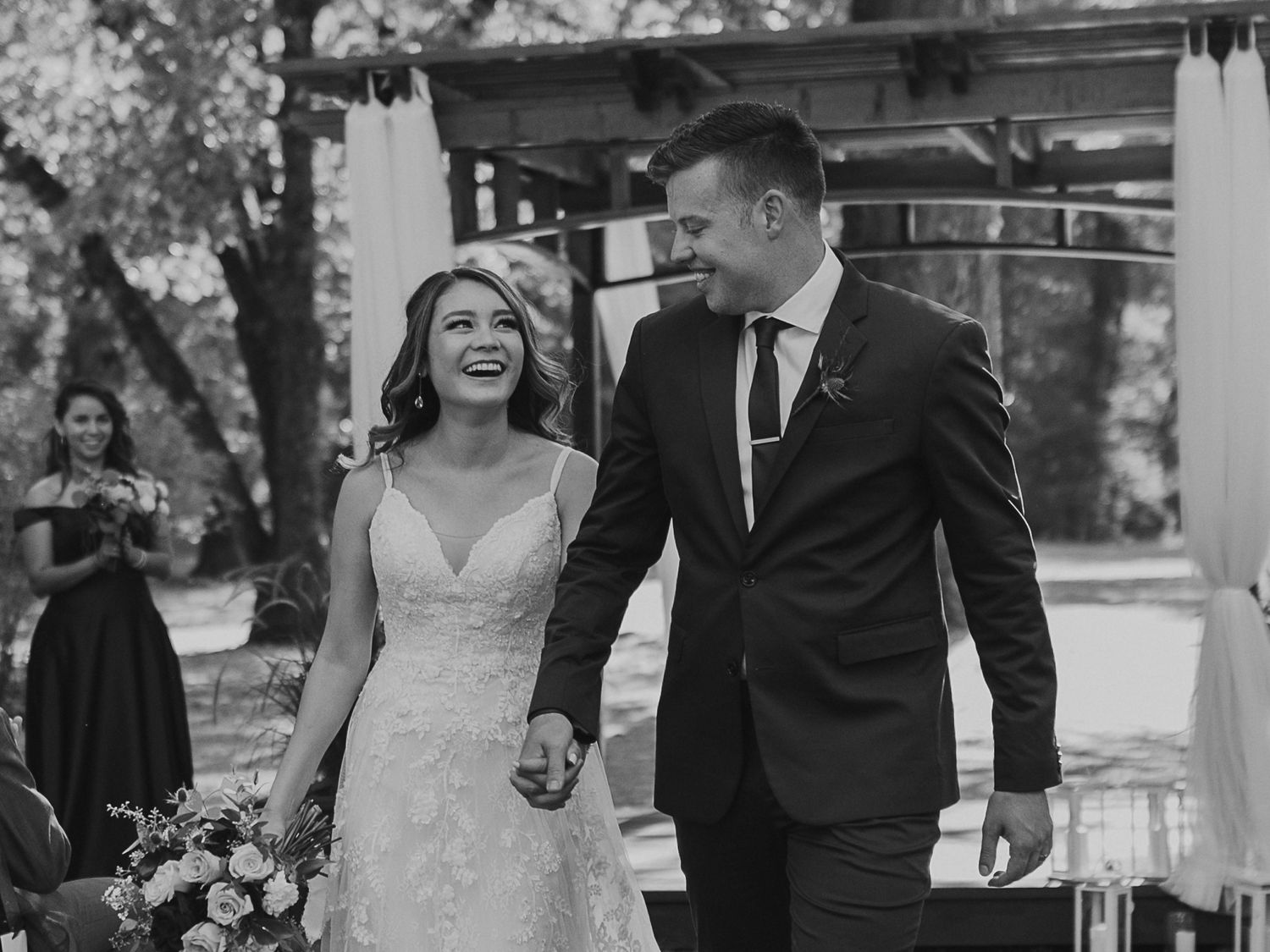 Black and white photo of newlyweds sharing a joyful moment during their outdoor ceremony.