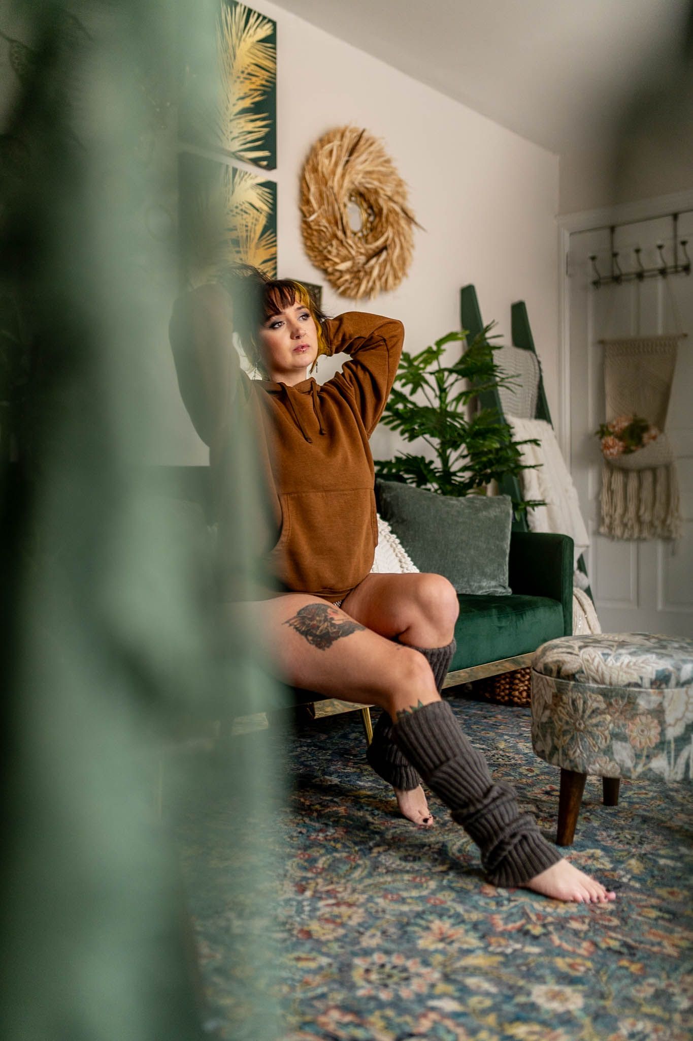 A model poses against a dark wooden wall background wearing black lingerie and tattoos.