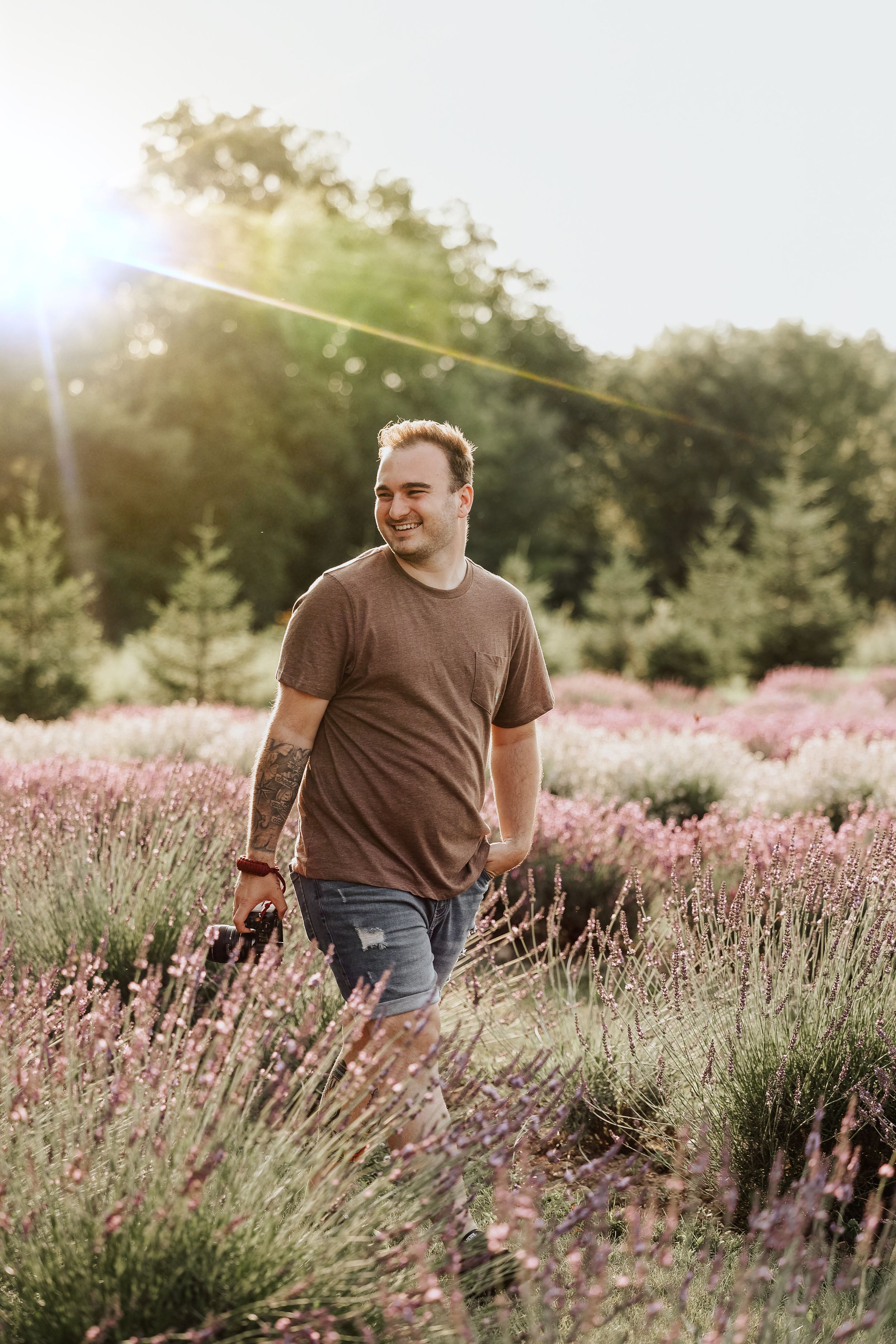 Man walking through blooming lavender field at sunset with warm golden lighting.
