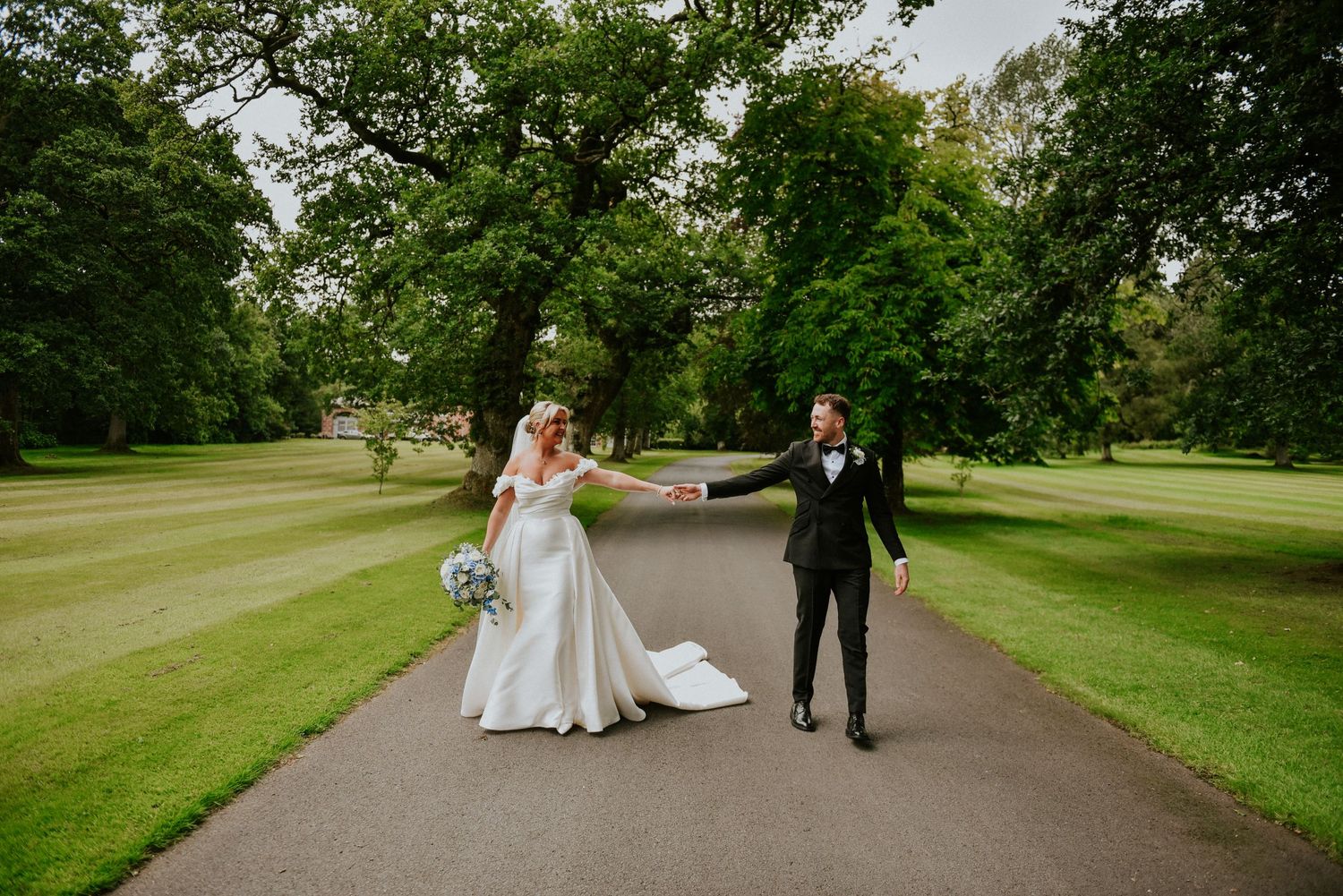 Bride and Groom in Wedding dress and Tuxedo walk along road at Lochgreen House Hotel in Troon Ayrshire