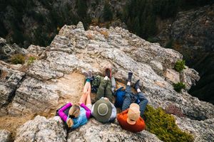Rock climbers scale a steep limestone cliff face while secured with ropes and safety gear.