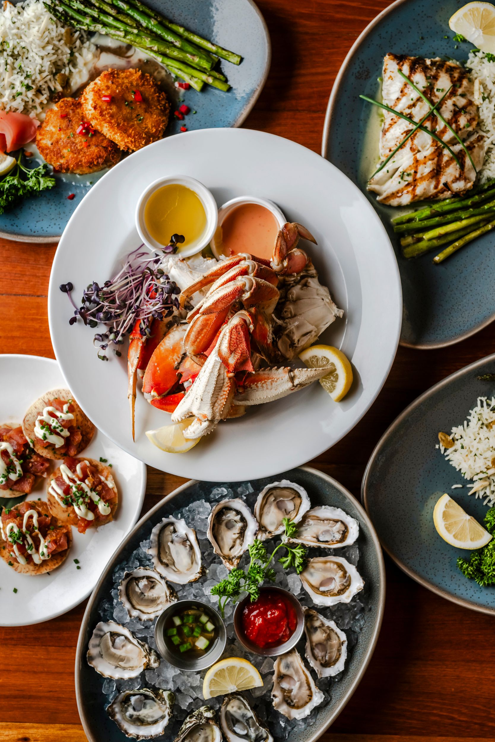 Seafood platter featuring crab legs, oysters, and grilled fish with various accompaniments.