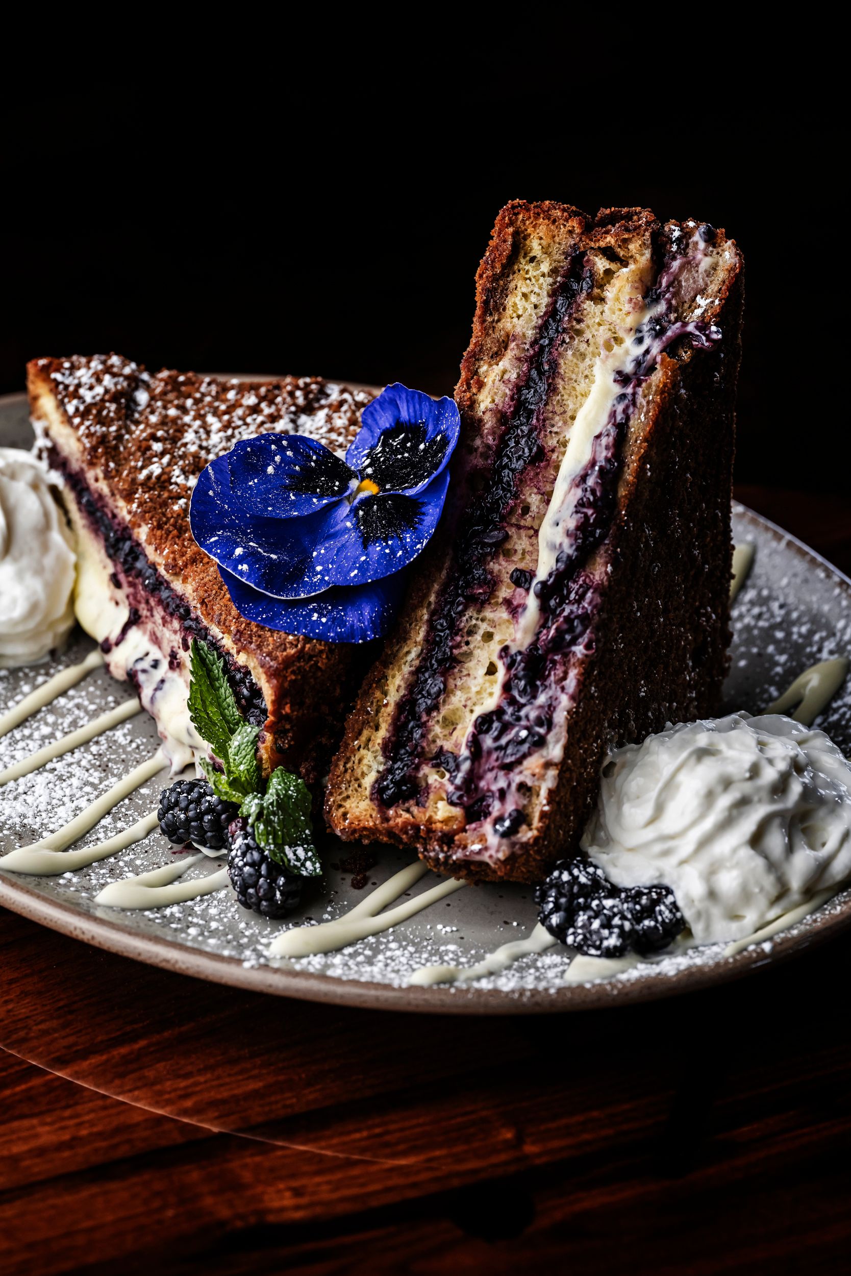 Decadent stuffed french toast garnished with blue flowers and whipped cream.