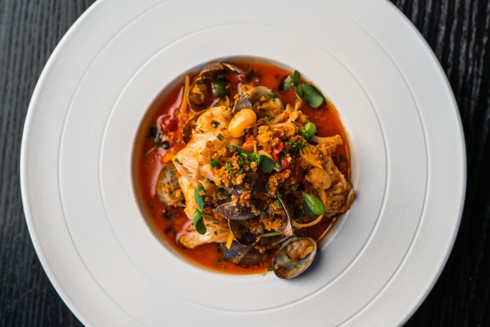 Seafood pasta dish with mussels in red sauce served in white bowl.