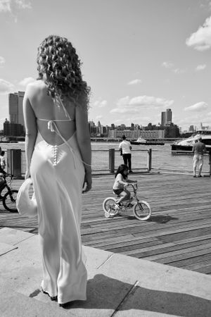 A black and white photo of people enjoying a sunny day on a waterfront boardwalk.