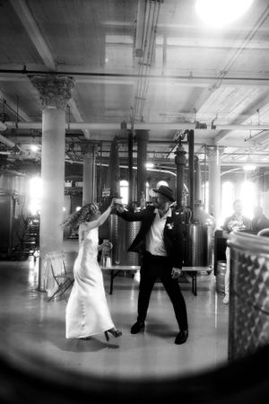 A black and white photo showing couples dancing in a spacious indoor venue.