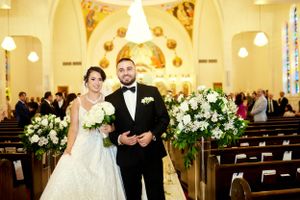 Wedding ceremony setting in church with floral arrangements lining the aisle.