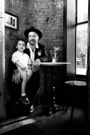 A black and white portrait in a rustic brick interior with vintage aesthetic.