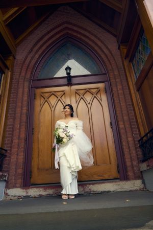 A wedding dress photograph taken at a dramatic angle beneath gothic church archways.