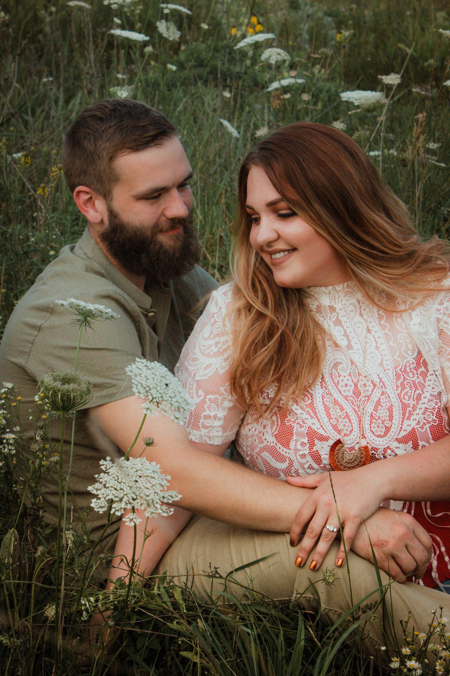 Couple sitting together in wildflower meadow during golden hour.