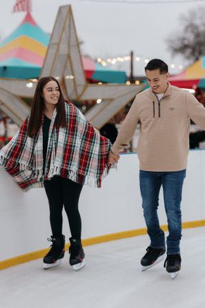 couple ice skating together outdoors and smiling