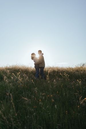 couple embracing in an open field during a couples portrait session at sunset