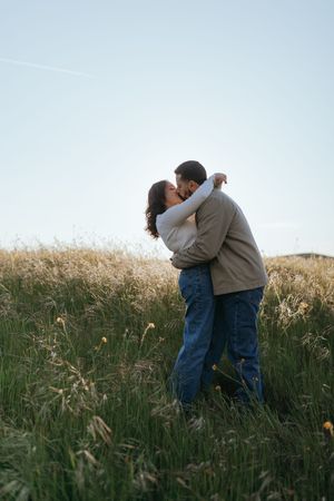 Couple standing close together in a grassy field during a couples portrait session