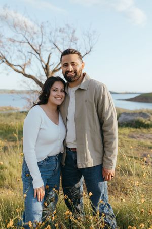 couple standing together outdoors in a grassy field of wildflowers