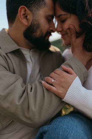 close up of a couple leaning forehead to forehead during a outdoor couples session, with one partner's hand showing an engagement ring