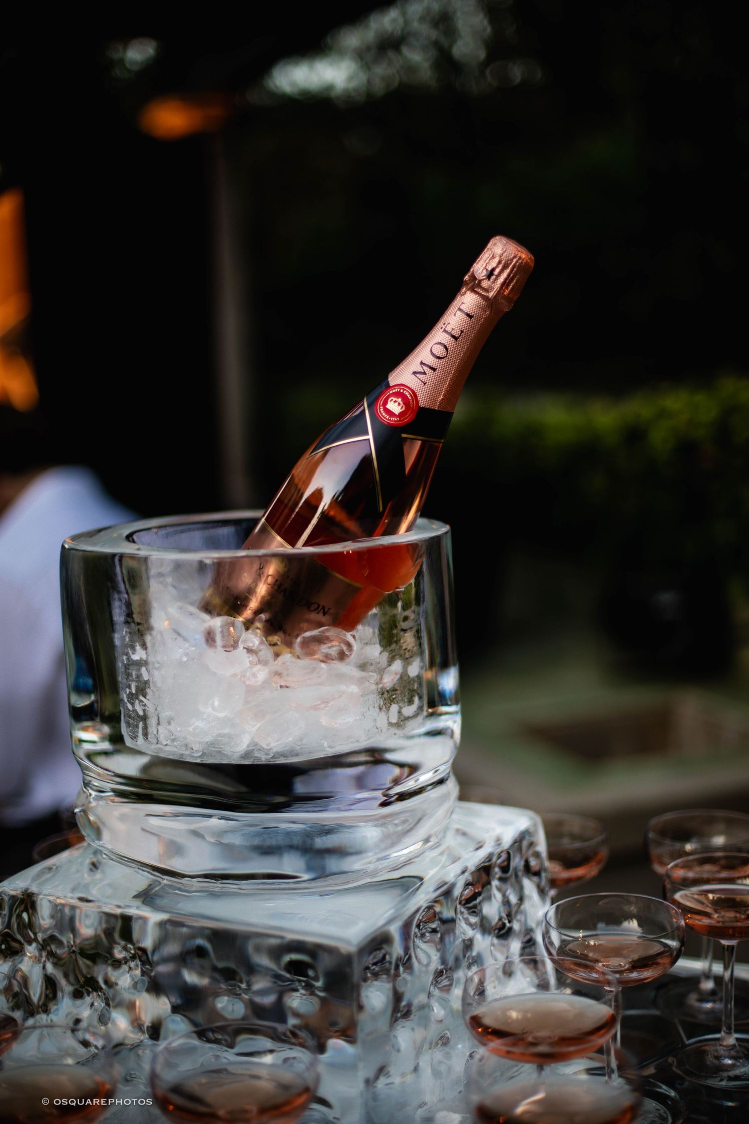 Bottles of champagne chilling on ice in elegant glass bowls at an upscale event setting.