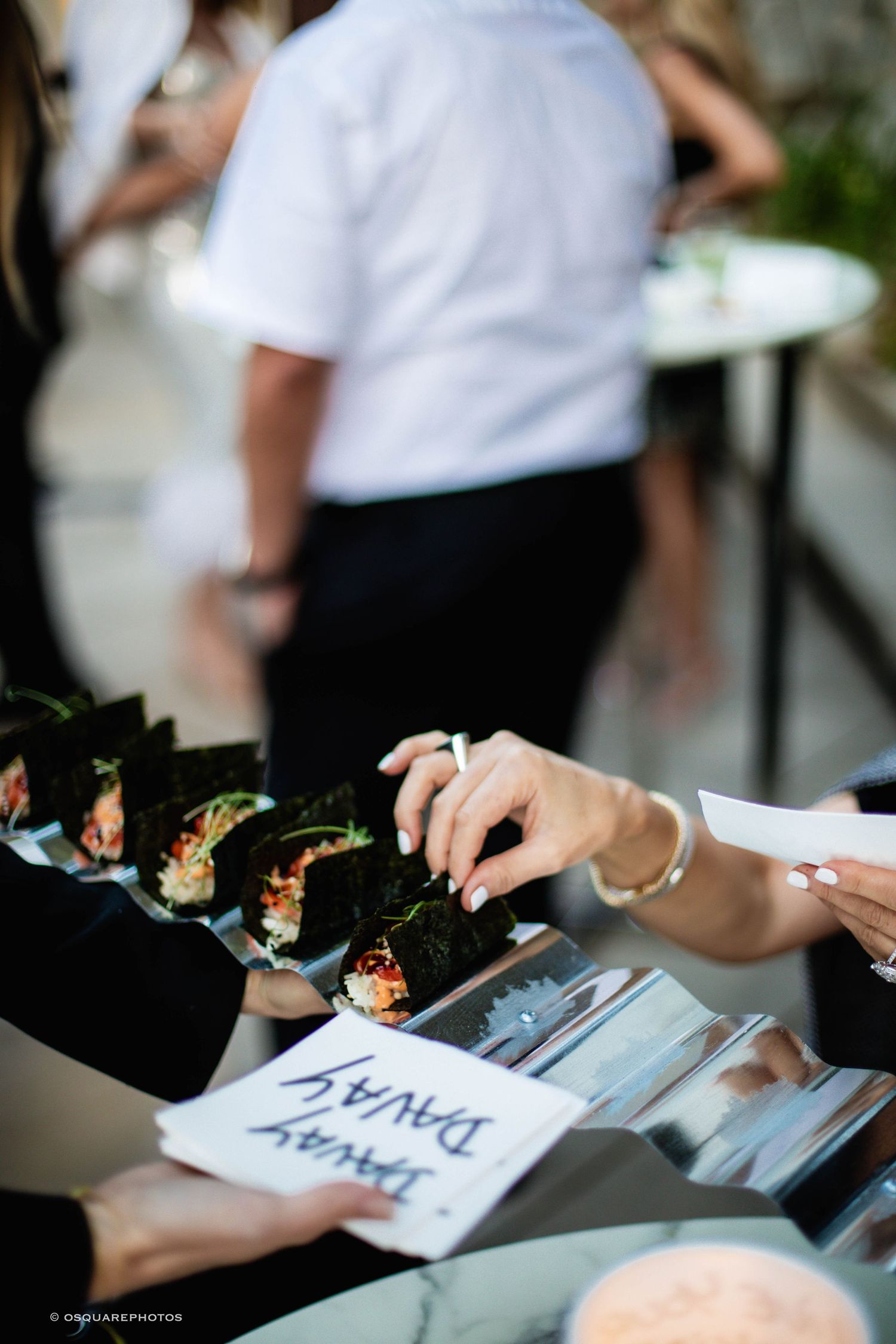 Hand-written name cards and place settings are arranged on a dark surface at an elegant event.
