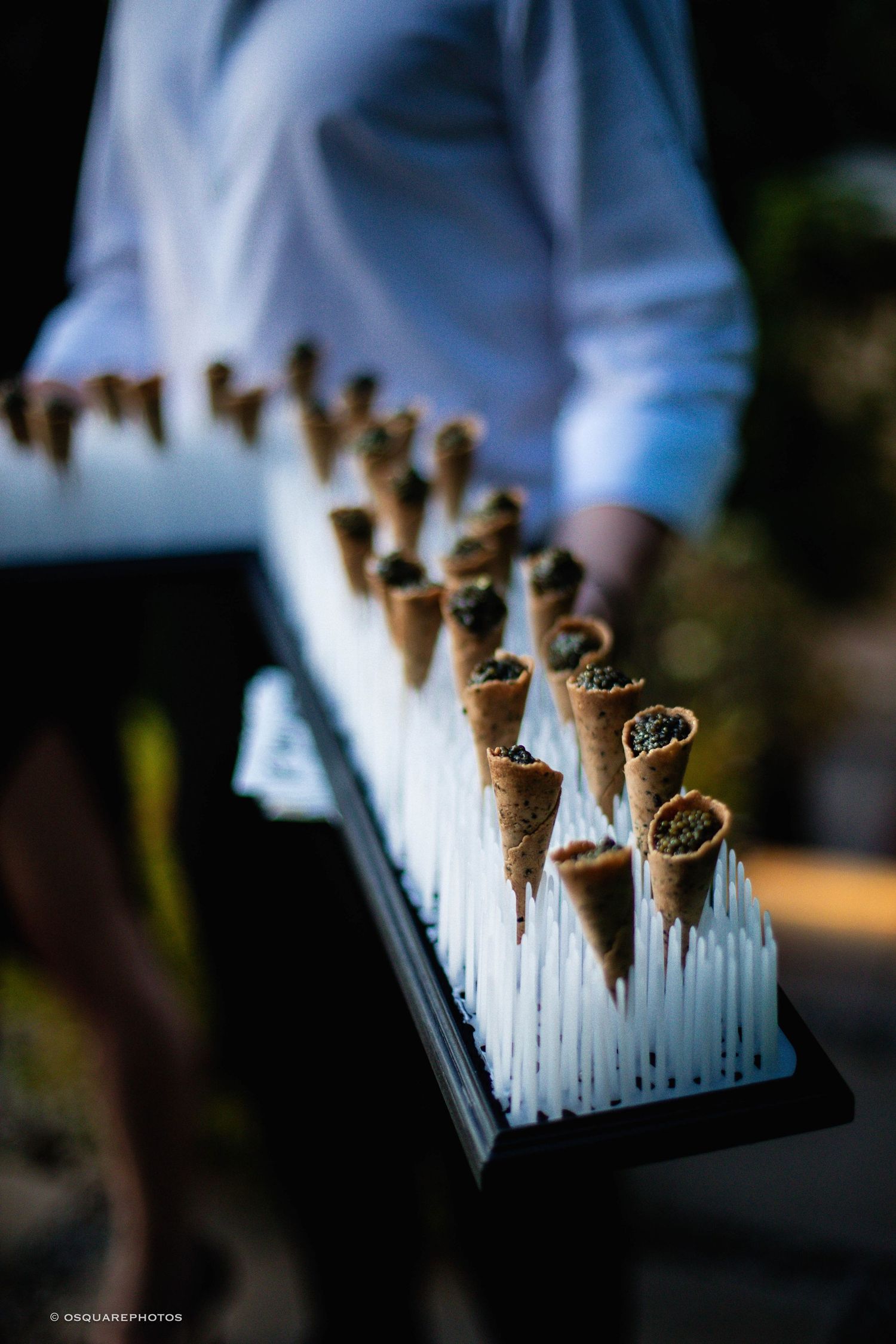 Small chocolate ice cream cones lined up in a row on a dark surface with shallow depth of field.