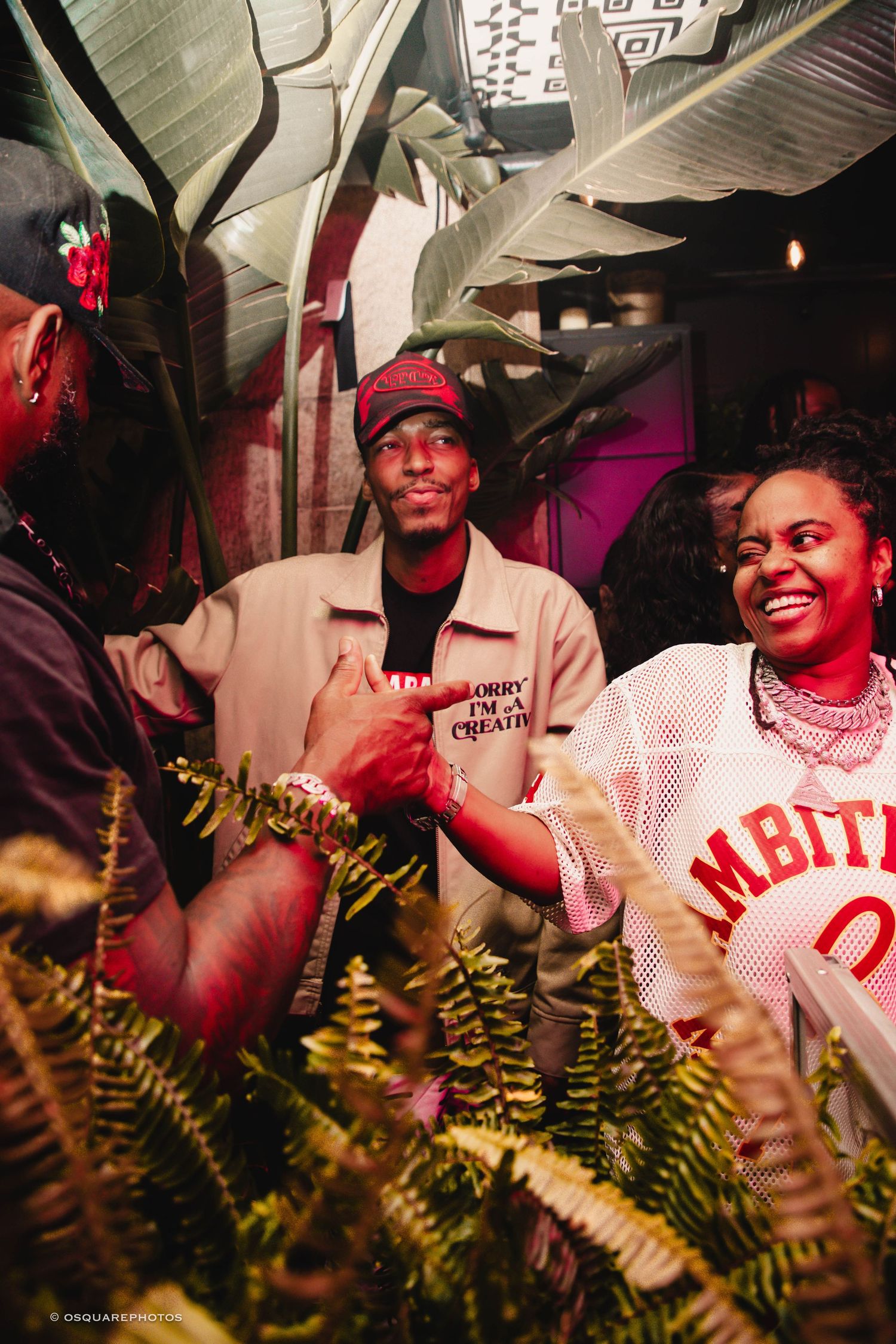 A sequence showing a couple in casual attire sharing joyful moments with ferns in the foreground at a dimly lit venue.