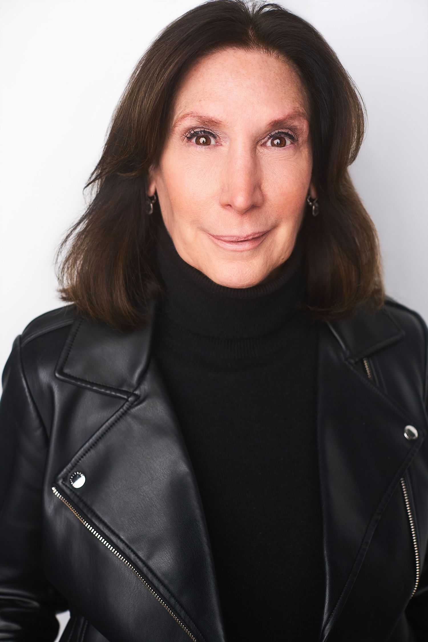 Corporate NYC headshot of a woman in a black turtleneck and leather jacket.