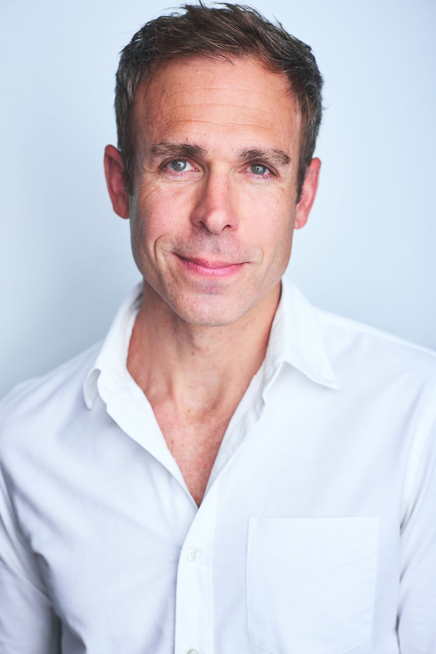Corporate NYC headshot of a man in a white collared shirt.