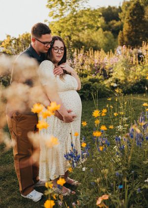 Expecting couple standing together among wildflowers during an outdoor maternity session