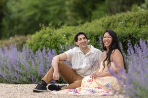 Couple sitting together laughing among purple lavender flowers outdoors.