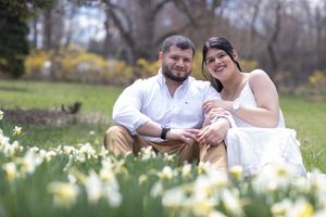 Couple sitting together smiling in a field of white daffodils in spring.